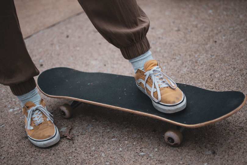 A Person in Yellow Sneakers Stepping on the Skateboard